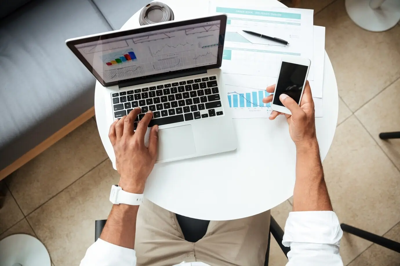 Bild aus der Vogelperspektive eines jungen afrikanischen Mannes, der beim Coworking sitzt.